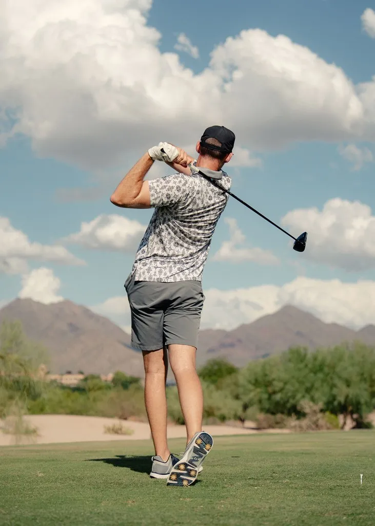 Golfer completing a drive in the desert